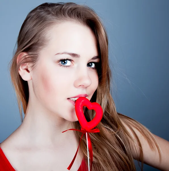 Beautiful young blonde holding a red heart — Stock Photo, Image