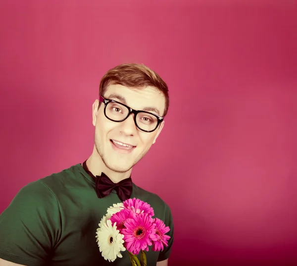 Jeune homme souriant tenant un bouquet de fleurs — Photo