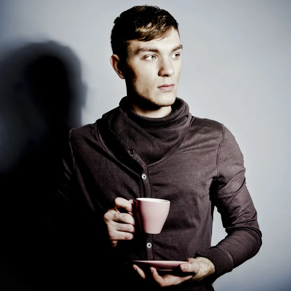 Молодой человек с чашкой кофе в руках — стоковое фото