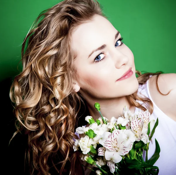 Ung kvinna med blommor på en grön bakgrund — Stockfoto