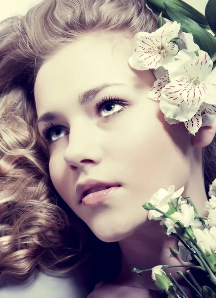 Güzellik yakın çekim portre genç bir kadın yüzüyle çiçekler — Stok fotoğraf