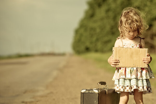 Lonely girl with suitcase standing about road