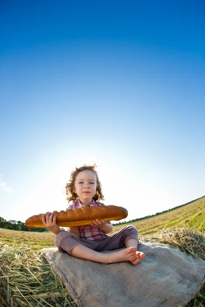 Παιδί που τρώει ψωμί στον τομέα του σίτου — Φωτογραφία Αρχείου