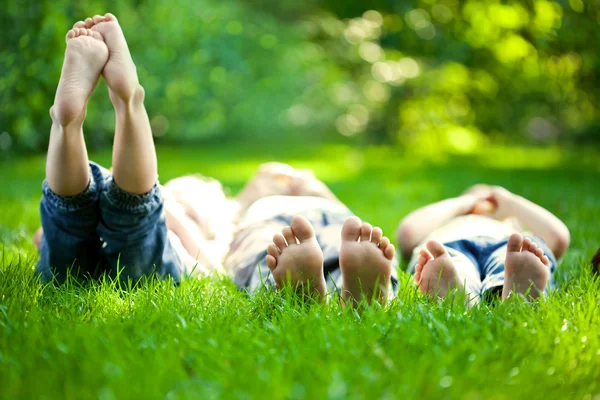 De gelukkige kinderen liggend op groen gras Stockafbeelding
