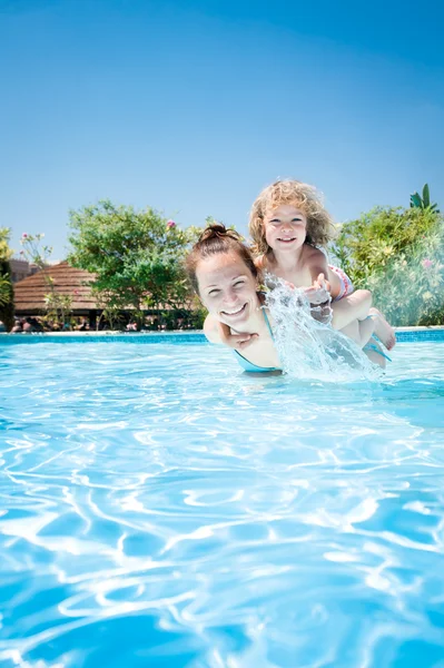 Счастливый ребенок играет с мамой в бассейне — стоковое фото