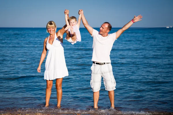 Счастливая семья играет на пляже — стоковое фото