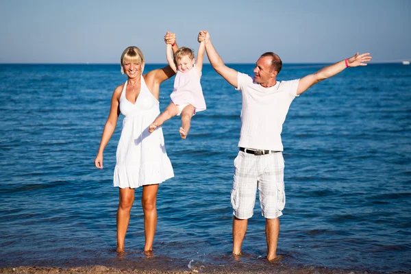 Família feliz brincando na praia — Fotografia de Stock