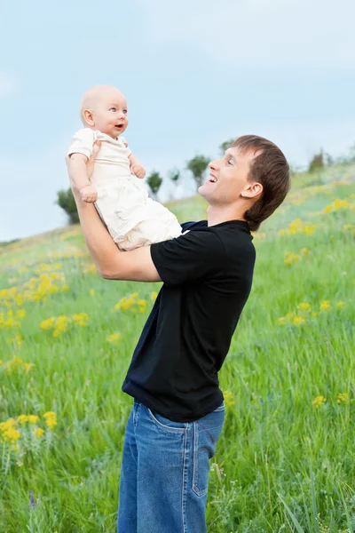 Щасливий молодий чоловік грає свого маленького хлопчика на природі на схилі — стокове фото