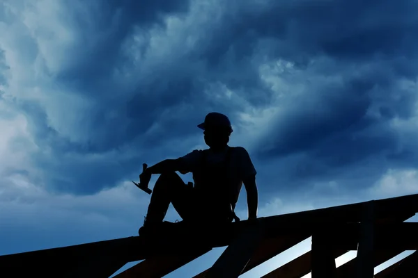 Construtor ou carpinteiro descansando no topo da estrutura do telhado — Fotografia de Stock