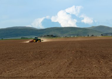 Tractor working the field till dusk clipart