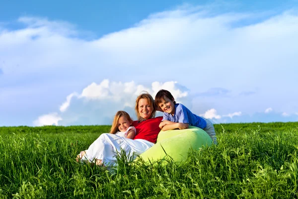 Crianças felizes e mulher sentada ao ar livre — Fotografia de Stock