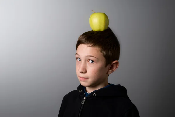 Мальчик с зеленым яблоком на голове — стоковое фото
