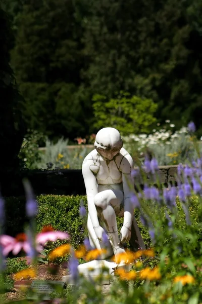 Estatua en un jardín de flores —  Fotos de Stock