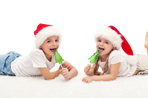 Szczęśliwe dzieci z santa kapelusze i słodycze — Zdjęcie stockowe