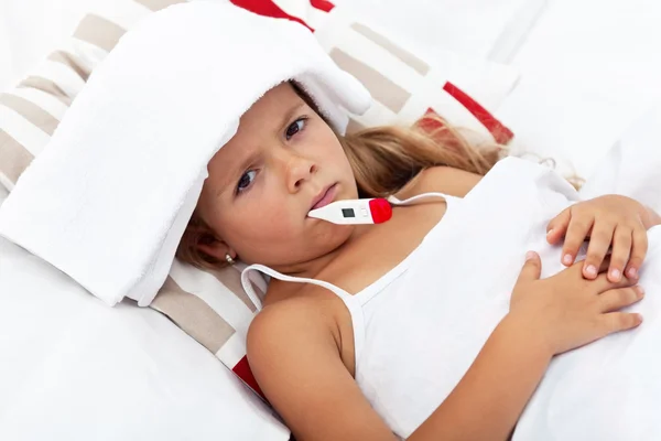 Krankes kleines Mädchen mit Thermometer und Kältepackung — Stockfoto