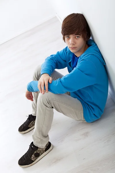 Tonåring pojke sitter på golvet vid väggen — Stockfoto