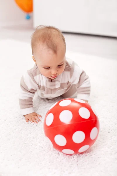 Bebê menina perseguindo uma bola vermelha — Fotografia de Stock