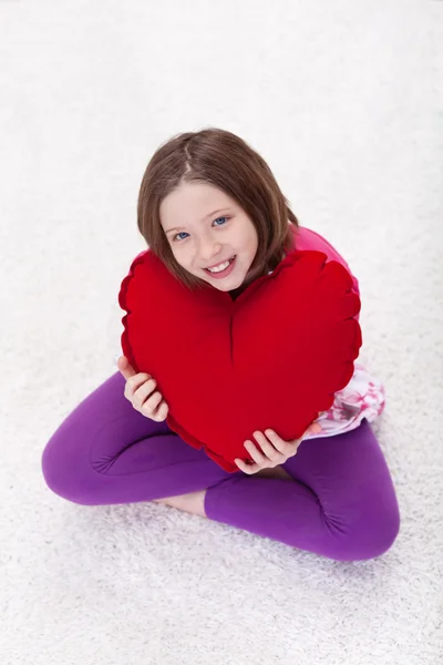 Giovane ragazza con grande cuscino cuore rosso — Foto Stock