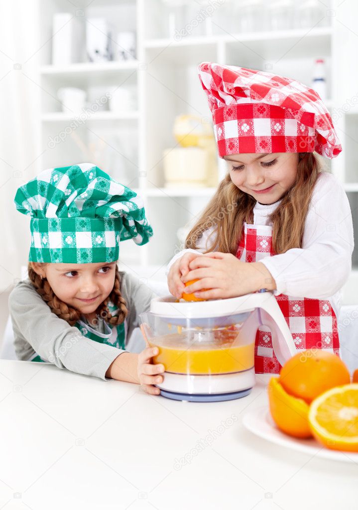 Little girls making fresh orange juice