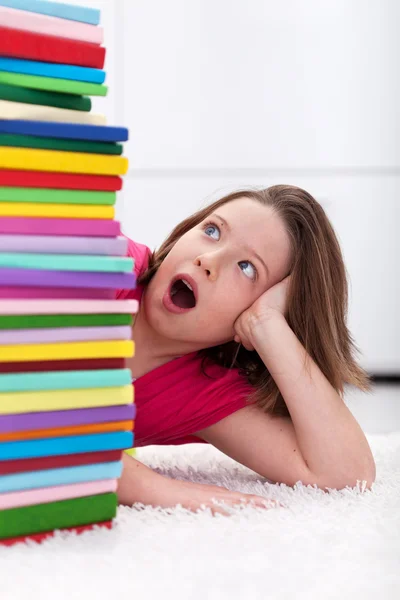 Jovem menina da escola chocado com a grande pilha de livros — Fotografia de Stock