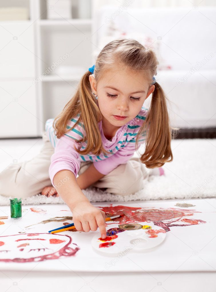 Little girl painting with finger