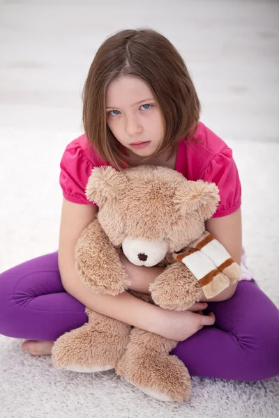 Sad young girl sitting with teddy bear — Stock Photo, Image