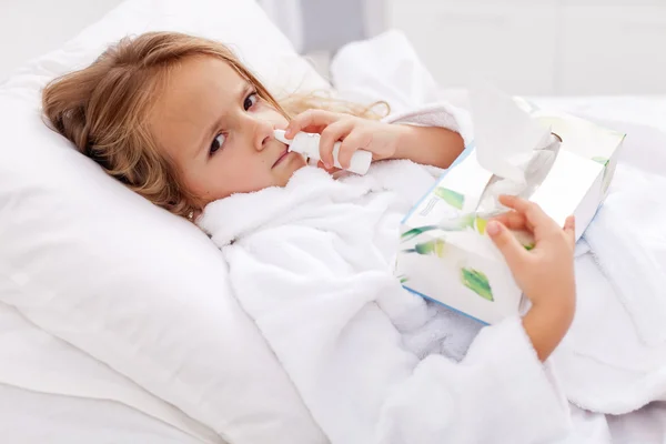 Kleines Mädchen mit schwerer Erkältung - mit Nasenspray und Papierservietten — Stockfoto