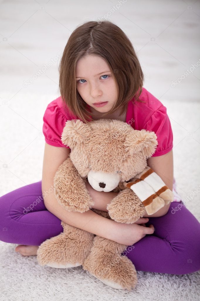 Sad young girl sitting with teddy bear