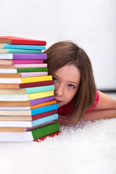 Mladá dívka schovává za knihy — Stock fotografie