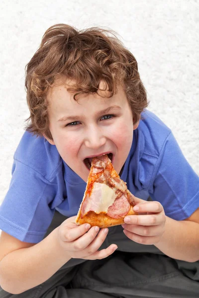 Miúdo faminto a comer pizza — Fotografia de Stock