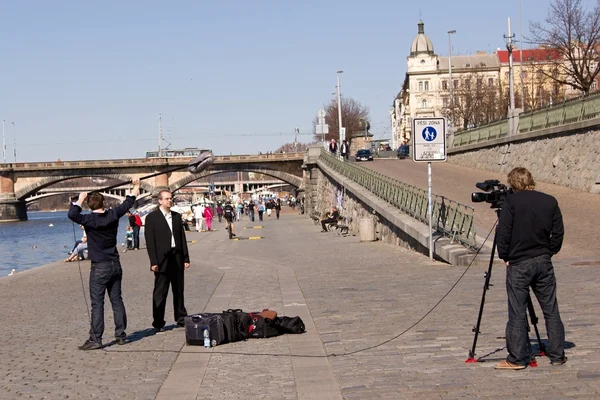 stock image Three-member television staff filming in Prague on the bank of Vltava river