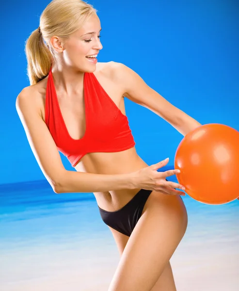 Ung kvinna leker med boll på stranden — Stockfoto