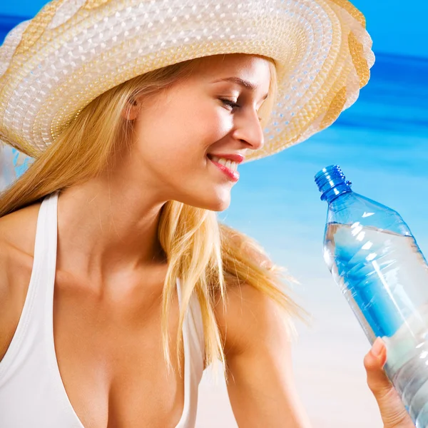 Женщина с бутылкой воды на пляже — стоковое фото
