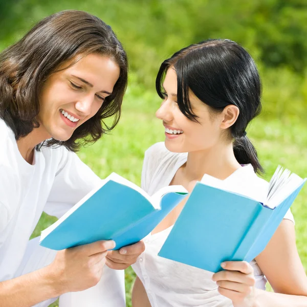 Молодая пара или студенты, читающие книгу — стоковое фото