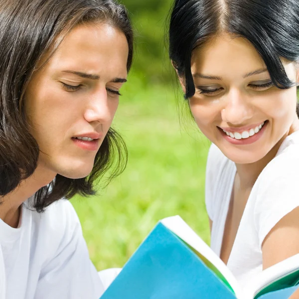 Jong koppel of studenten, lezen van een boek — Stockfoto