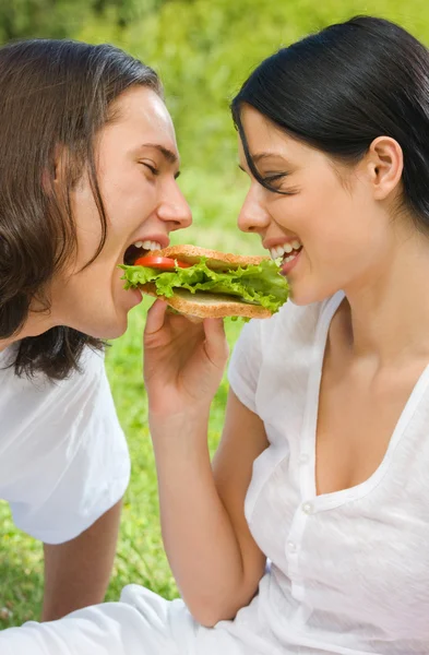 Casal jovem comendo juntos ao ar livre — Fotografia de Stock
