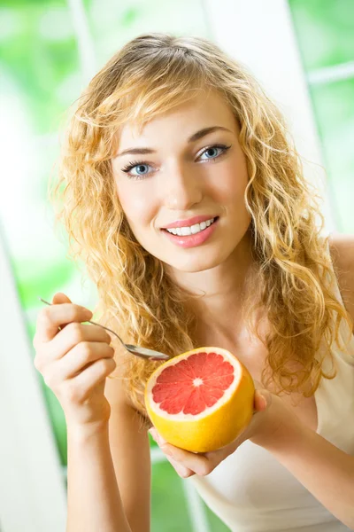 Jonge vrouw met grapefruit thuis — Stockfoto