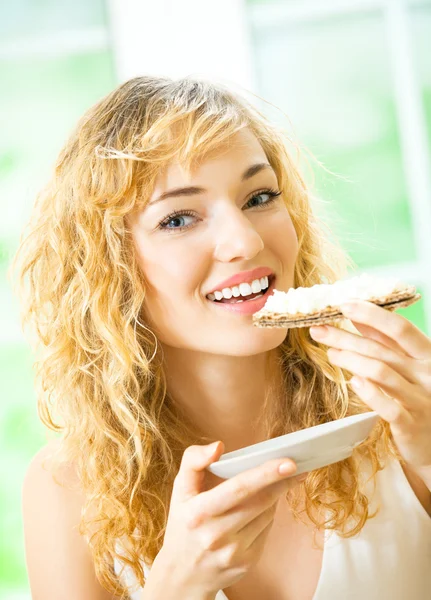 Frau isst Knäckebrot mit Käse zu Hause — Stockfoto