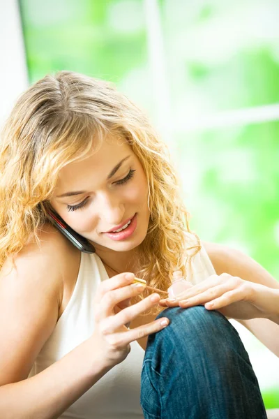 Женщина делает маникюр и разговаривает по мобильному телефону — стоковое фото