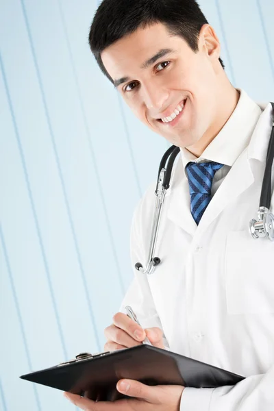 Médico feliz com caneta e área de transferência no escritório — Fotografia de Stock