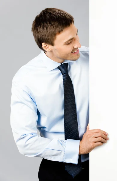 Affärsman som visar skylt, på grå — Stockfoto