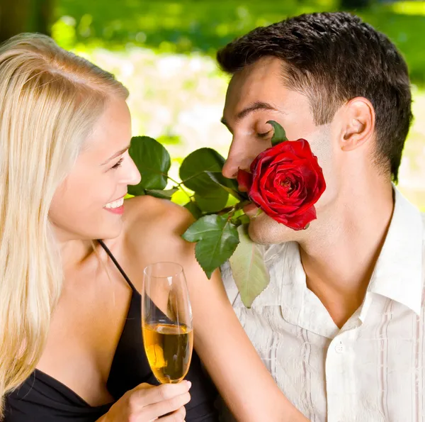 Casal com copos de champanhe e rosa, ao ar livre — Fotografia de Stock