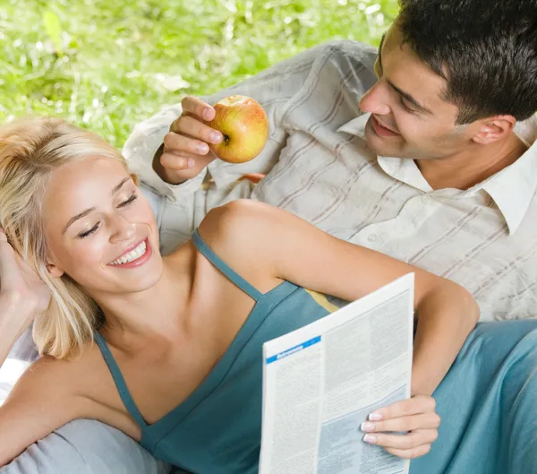 Jeune couple joyeux lecture, à l'extérieur — Photo