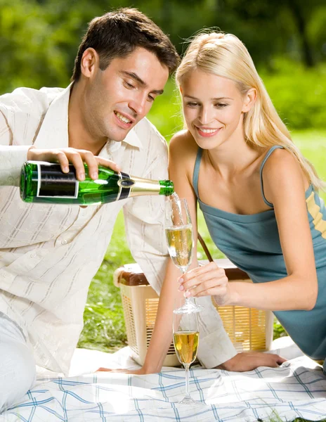 Jong koppel met champagne op picnic, buitenshuis Stockfoto