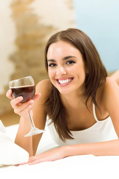 Kadın yatakta kırmızı şarap ile — Stok fotoğraf