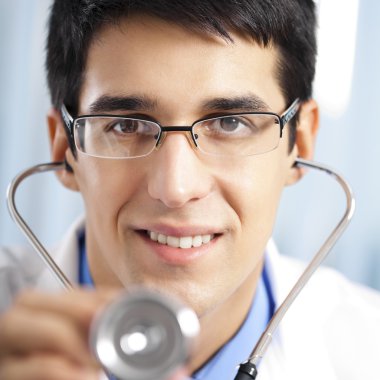 Happy doctor with stethoscope, at office clipart