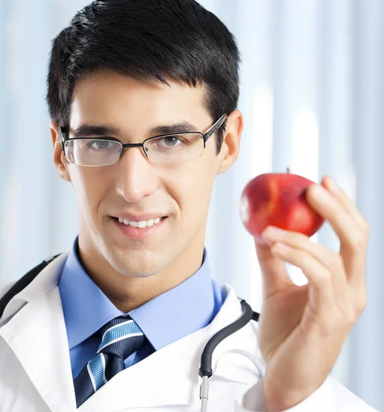 Leende läkare med apple, på kontor — Stockfoto