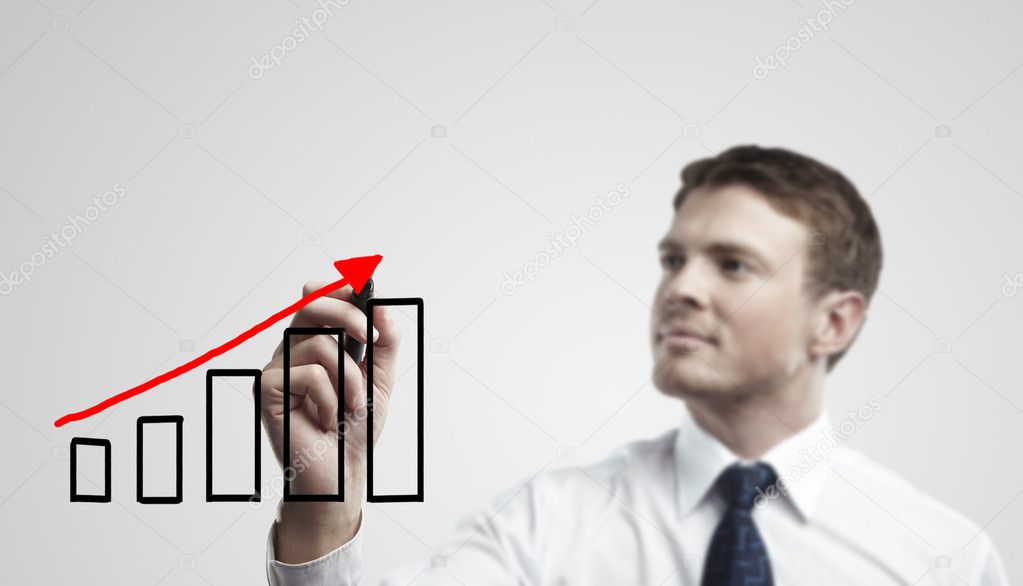 Young business man drawing a rise graph on a glass window in an office