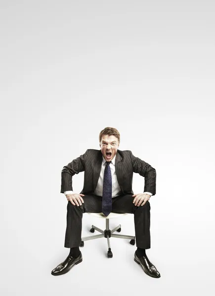 Młody biznesmen, krzycząc i siedzi na krześle. — Zdjęcie stockowe
