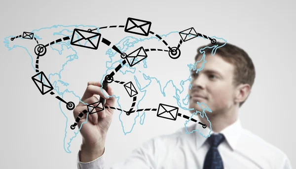 Young business man drawing a global network with envelopes on world map — Stock Photo, Image